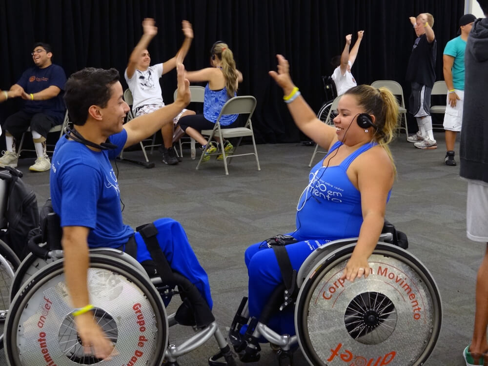 Two people in wheelchairs, facing each other and dancing.