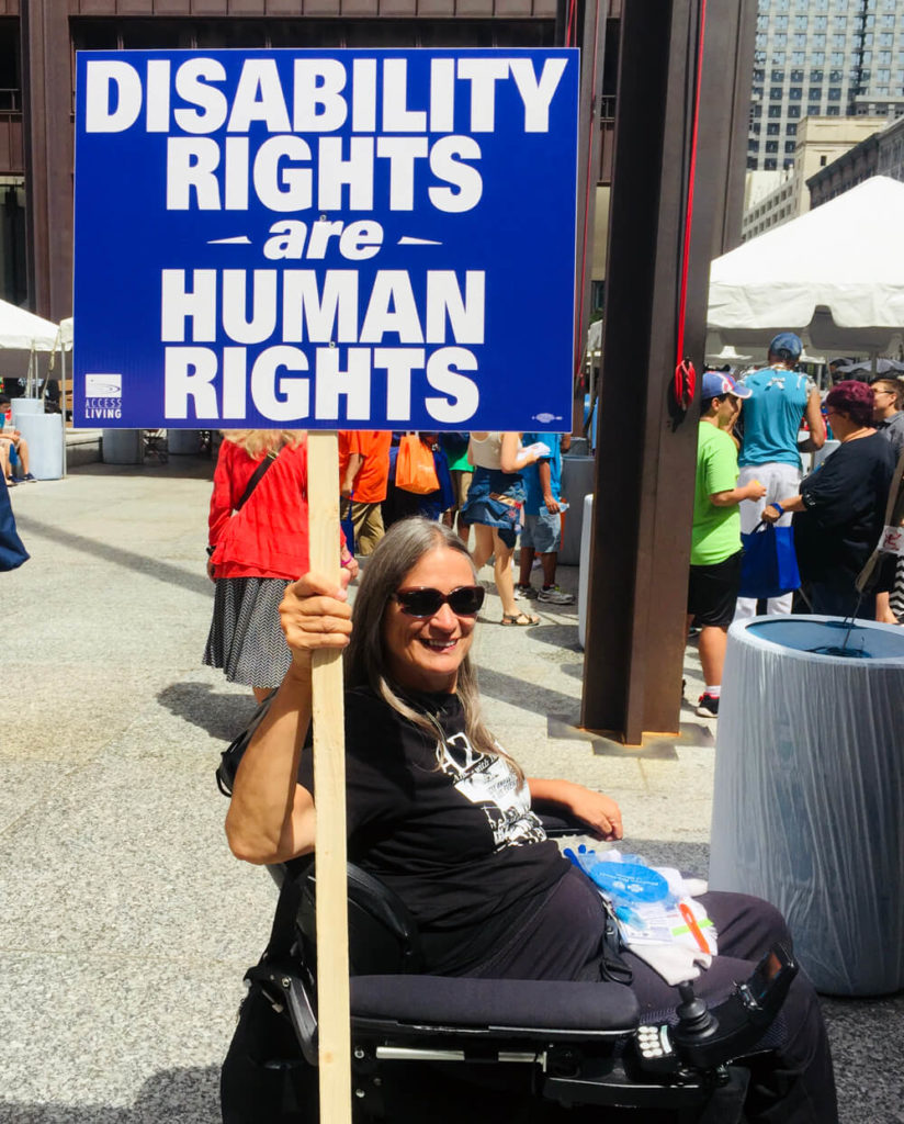 Woman in a wheelchair holds a sign that reads disability rights are human rights.