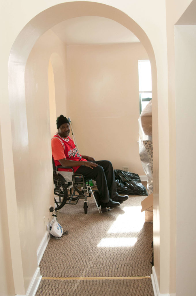 Man in wheelchair sits surrounded by boxes as he unpacks. 