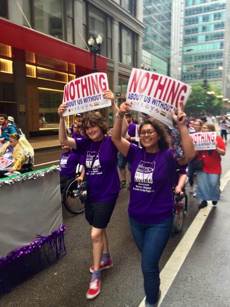 Disability advocacy: smiling woman and girl carrying signs in a parade.