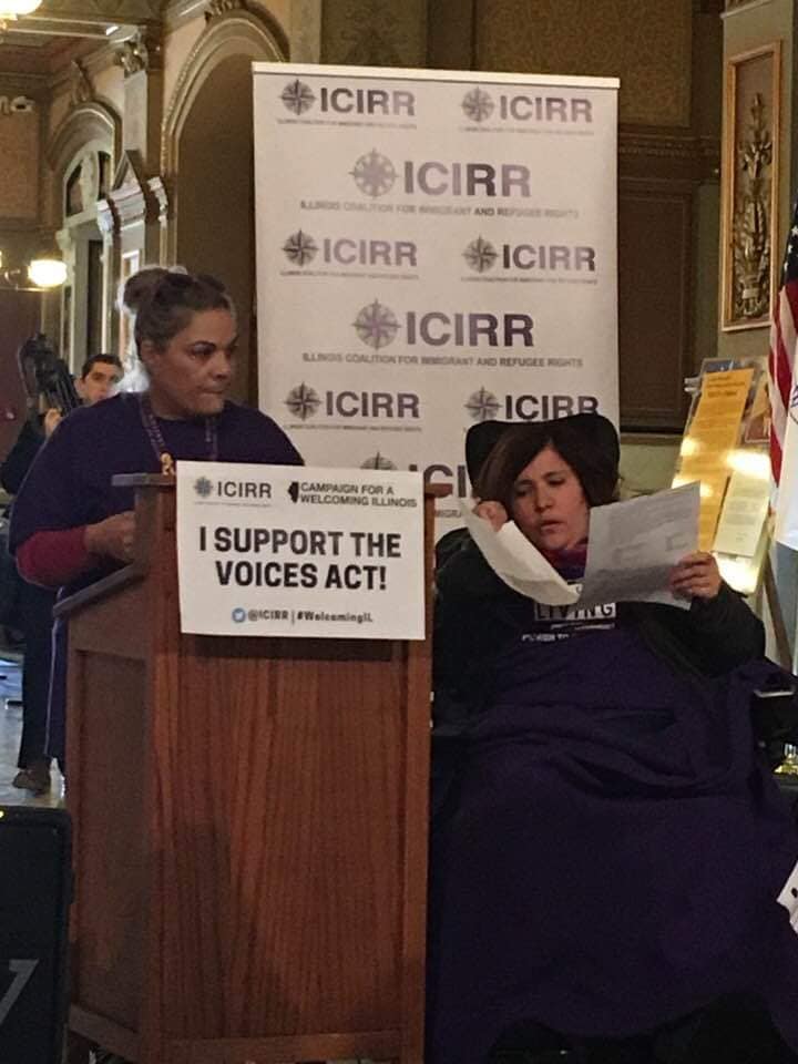 Woman speaks at a podium alongside a woman in a wheelchair.