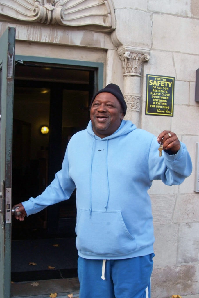 An Access Living consumer smiles as he holds up the keys to his new home.