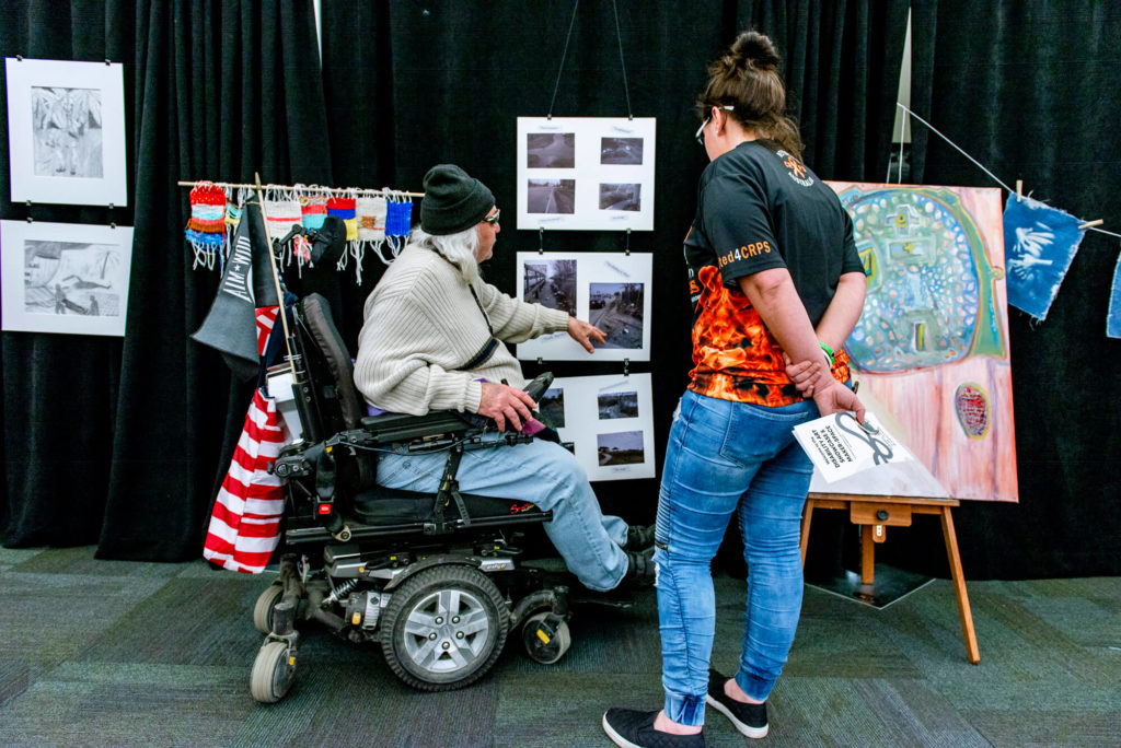 Attendees of an art showcase examine displayed artwork.