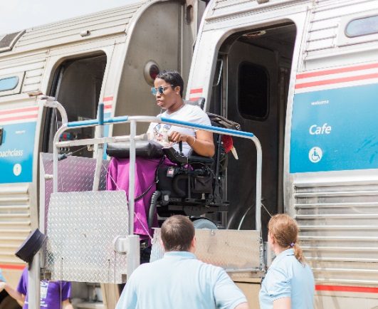 A wheelchair user using a wheelchair lift to disembark from a train.