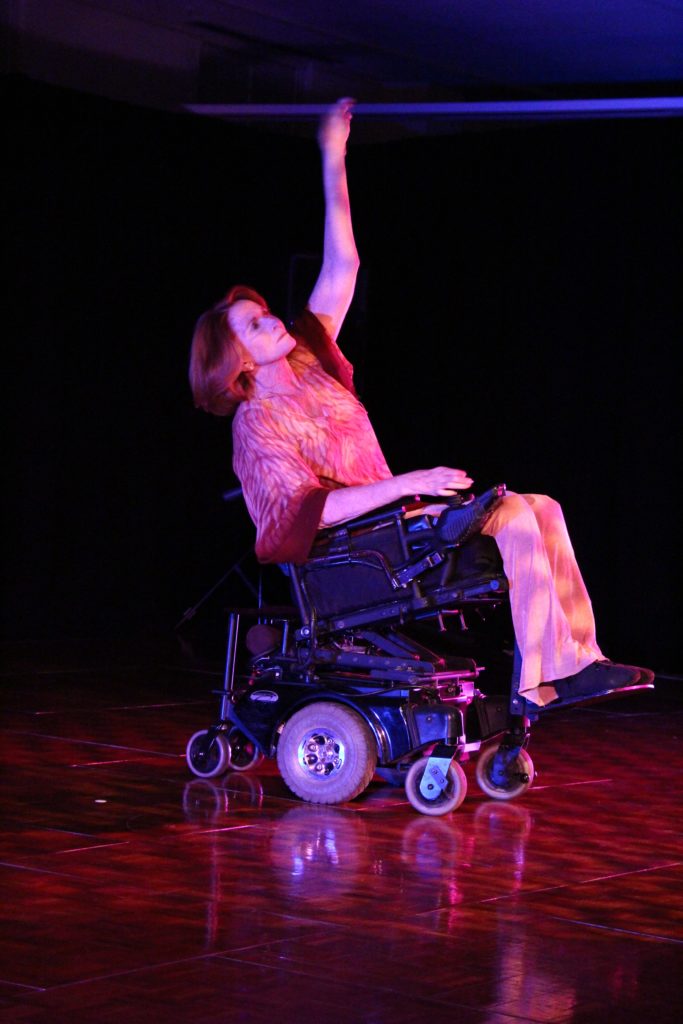 A woman performing an integrated dance. She uses a power wheelchair.
