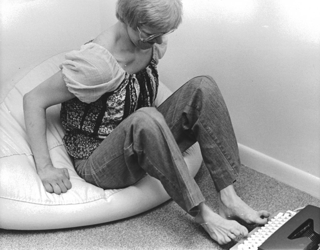 A woman uses her toes to operate a typewriter.