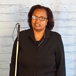 Denise Avant, a Black woman wearing glasses and holding a white cane.