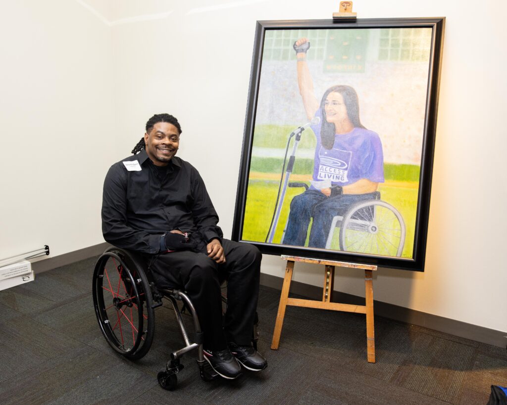 Black man in wheelchair sits by painting.