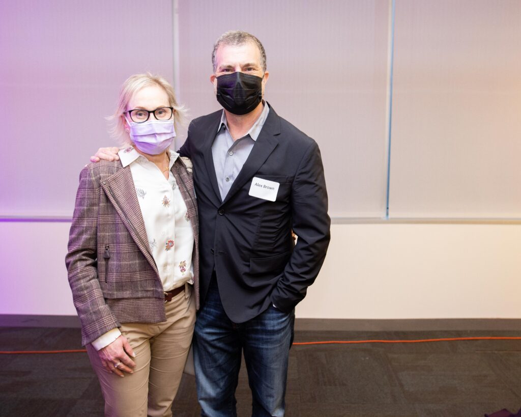 Man and woman wearing masks pose at reception.