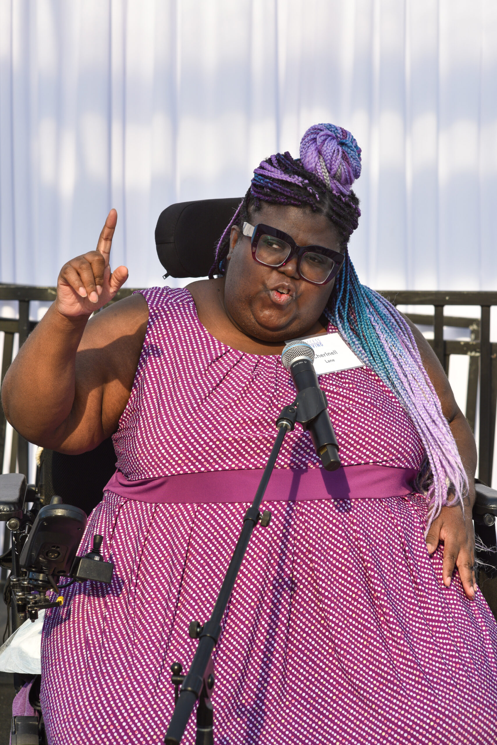 Black woman in wheelchair at a microphone