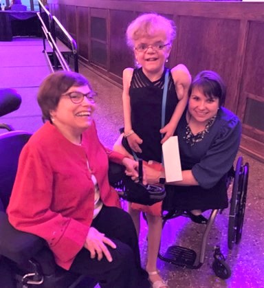 Judy Heumann posing for a photo with Karen Tamley and Karen's daughter, Dominicka.