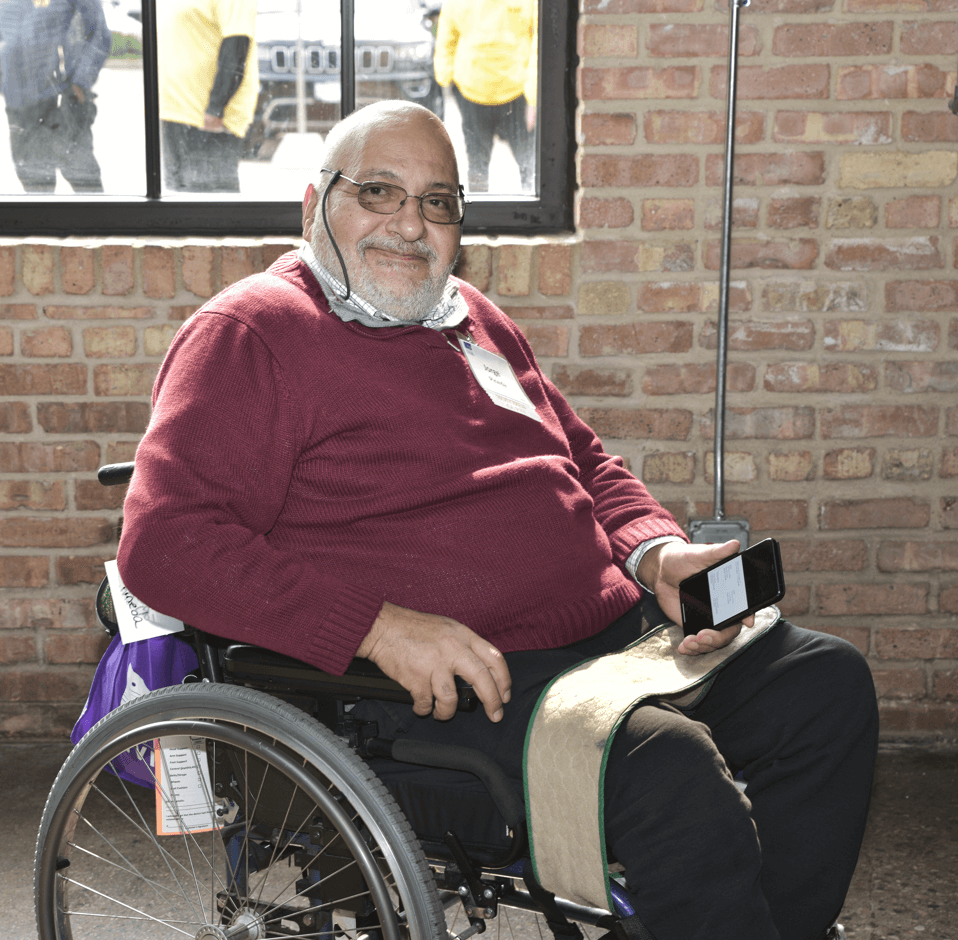 Honored guest Jorge Pineda, a wheelchair user, smiles at the camera from in front of a window.