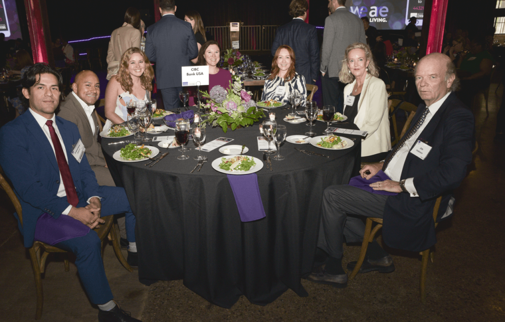 A group shot of several gala sponsors during dinner. The sign on their table reads "CIBC Bank USE"