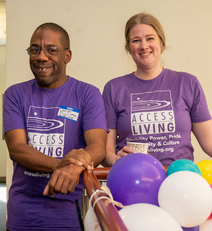Two people - an Access Living consumer and a staff member - standing and smiling in front of balloons