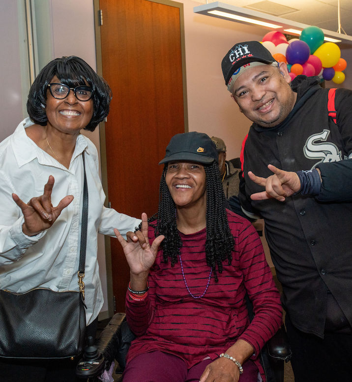 Group of people smiling and signing “I love you” in American Sign Language