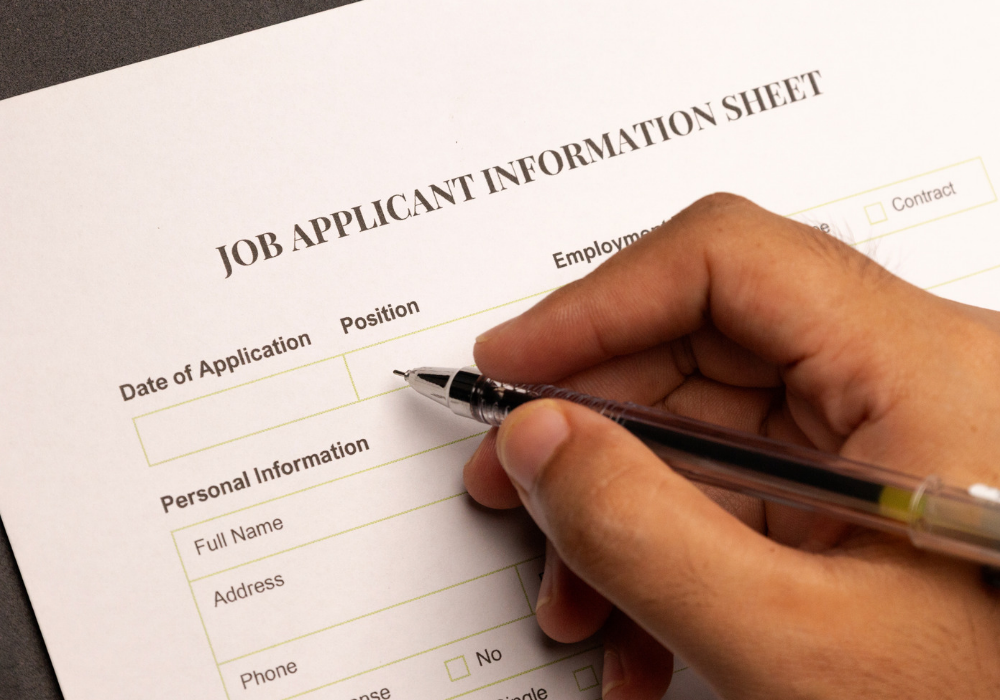 Photo of a hand holding a pencil and filling out a job application